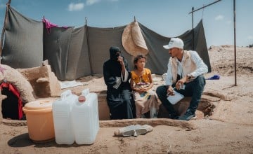 Internally displaced mother with her child received hygiene/cholera kit and sitting beside her underground/caved home (made by family to protect from extreme weather conditions) in Al-Salam IDP site. (Photo: Ammar Khalaf/Concern Worldwide)