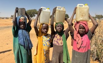 Children carry containers of water after filling them at a UNICEF borehole inside Adré refugee settlement in Chad