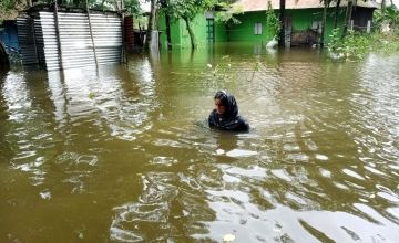 Woman wading through water up to her shoulders in Bangladseh