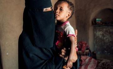 Oma, an 18-month-old girl who had suffered acute malnutrition, is held by her mother during a follow-up visit by Saadia, a Community Health Volunteer, in Yemen. Photo: Ammar Khalaf/Concern Worldwide