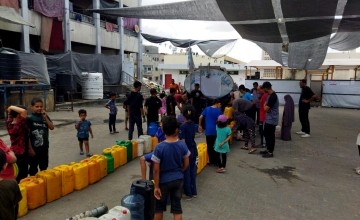 People queuing with water containers at a water truck in North Gaza