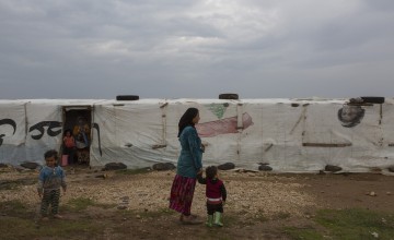 A Syrian refugee woman stands with her child in front of her tent in the village of Shir Hmyrin