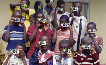 Group of children taking pictures with disposable cameras in Rwandan orphanage