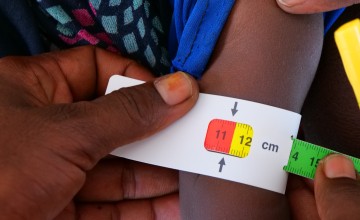A Middle-Upper-Arm-Circumference (MUAC) band being applied to a child (not Abdul). The red indicates severe acute malnutrition. The yellow indicates risk of acute malnutrition. Green means normal, well nourished. Photo: Eugene Ikua/Concern Worldwide 