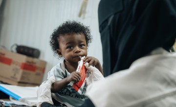 Basam* (10 months) eating nutritional supplements at Concern supported health clinic in one of the displacement camps in Lahj Governorate, Yemen