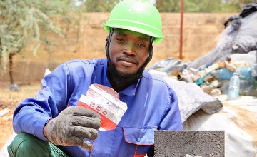 Karö Enterprise employee Maigao César holds an empty Plumpy’Nut (RUTF) packet collected from nutrition centres in Lake Chad. These packets, often discarded after use, are repurposed here as raw material for the production of eco-friendly bricks and paving stones, helping to reduce plastic pollution. Photo: Pierre Maget/Concern Worldwide
