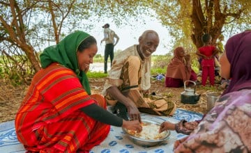 Concern Communications Officer Kalkidan Jabir shares a meal with Hussein Abdulahi Hussein and his wife Nadifa Yusuf and their family in Alloley Kebele, Dollo Bay District in the Somali Region of Ethiopia. Hussein leads a group of 45 farmers who are part of an agriculture group supported by the Hannano Programme. With this support, they received improved variety of seeds, a generator, fuel, water pumps, and training. Photo: Adnan Ahmed/Concern Worldwide