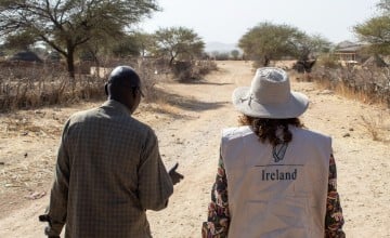 Concern staff member and representative from Irish Embassy to Sudan walk down a sandy road in Sira, Chad