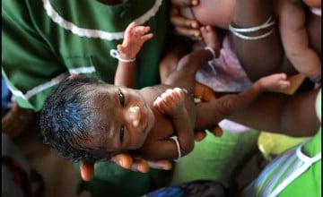 Three-day-old Umaro Monsaray is held by nurses during his health check at the Magburaka Primary Health Clinic, in Tonkolili. (Photo: Brenda Fitzsimons/The Irish Times)
