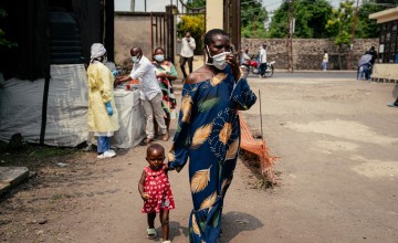 A woman wearing a mask as a preventive measure enters Kyeshero Hospital after passing a checkpoint for hand washing and health screening in Goma