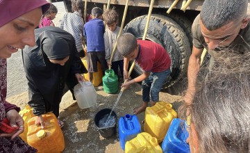 People gather to fill containers with clean water from a tank.
