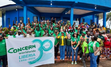 Around 60 people dressed in the green of Concern Worldwide, outside a blue building in Buchanan, LIberia.