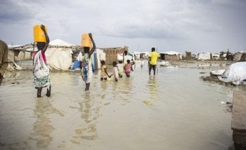 Women walk through contaminated flood waters in a camp in South Sudan.