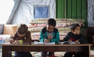 Syrian refugee children write on their notebooks during class at an informal tented settlement in Akkar, Lebanon. Photo taken by Dalia Khamissy / Concern Worldwide.