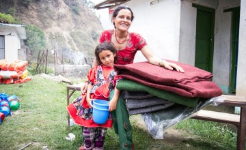 Chameli Darji with her youngest daughter, Apita, with the items they received at a Concern Worldwide and Rural Reconstruction Nepal (RRN) distribution in Talamarang VDC in Sindhupalchok district, Nepal. Photo taken by Crystal Wells / Concern Worldwide.