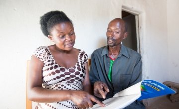 Stanislas Iriboneye participated in Concern’s Graduation programme in Rwanda. He is pictured here with his case worker, Gisèle Umumararungu, who is reviewing his financial plans. Photo: Robin Wyatt / Concern Worldwide, 2015. 