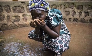 A woman drinks water from one of four new water sources that Concern Worldwide rehabilitated around Dawili, which sits between the towns of Bokoum and Bossembele in Ombella-M'Poko prefecture in southern Central African Republic. Photo taken by Crystal Wells / Concern Worldwide.