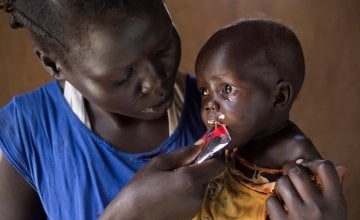 Little Adut is fed vitamin-packed therapeutic paste by her mum Aweng Aken as part of a Concern-funded malnutrition programme. Photo: Kieran McConville, South Sudan, 2016.