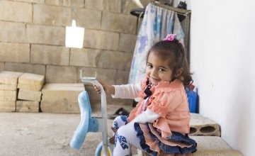 Two and a half year old Oula* plays with her favourite toy, outside her newly rehabilitated home in northern Lebanon. Photo: Chantale Fahmi/Concern Worldwide 2017.