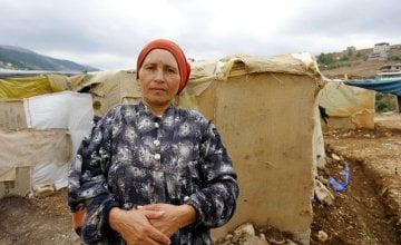 A 55-year old Syrian refugee stands in front of her makeshift shelter in an informal tented settlement near the Syrian border in north Lebanon, February 2015. Photo taken by Dalia Khamissy / Concern Worldwide.