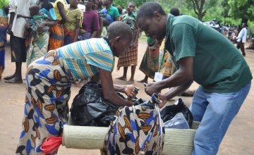 Johannes Chikarate helps a women who has been displaced due to the floods in Malawi to pack up the items she has received from Concern in Nsanje District. Credit: Deborah Underdown / Concern Worldwide.