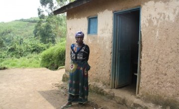 Sarah Nyirabagende stands outside her home in Kazinga Village. Photo taken by Concern Worldwide.