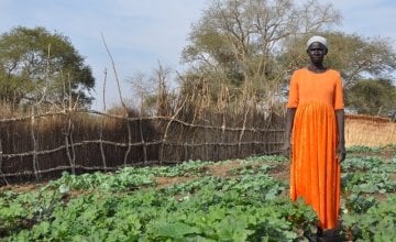 Namia stands proudly next to the vegetable garden she grew with the help of Concern. Photo taken by Deborah Underdown.