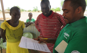 Dr Francis Nkakojoo, Concern’s Health and Nutrition Programme Manager with Mary Nyandit and Mol Garang providing advice on completing reports on screenings for malnutrition at Mayen Ulem Primary Health Care Centre