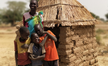 One of our beneficiaries, Theresa Abuk Dut, with her three sons outside their newly-constructed household latrine. Photo: Malek Deng Aguot