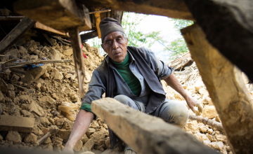 Seventy-year-old Krishna Prasad Sapkota digs through the mud and stones of what used to be his home to see if any belongings can be recovered. Photo taken by Crystal Wells/Concern Worldwide