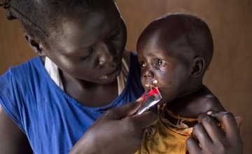 Aweng Ayii (25) and her 10-month-old daughter, Adut Ayii Garang,at their home in Nyamel, Northern Bahr el Ghazal in South Sudan. Aweng is feeding her ready-to-eat therapeutic food (RUTF), supplied as part of the programme. Photo: Kieran McConville/Concern Worldwide.