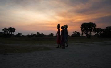 Women crossing in Leer County, Unity State, South Sudan at sunset. Deep in the swamps, the island has become a haven for thousands of people fleeing conflict. Photo: Kieran McConville/Concern Worldwide