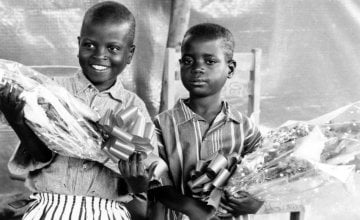 Two children hold flowers at the Runda transition camp in Rwanda. Photo: Concern Worldwide (1997)