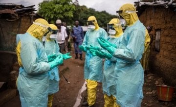 A burial team pray before they collect a corpse from inside a house in the east of Freetown Sierra Leone in 2015 Ebola outbreak. Photograph: Michael Duff