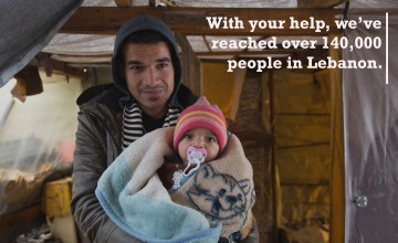 Syrian refugee Ahmad, 22, holds his cousin's baby Amin, 5 months, as he stands at the entrance of his tent in an informal tented settlement in Mohamara, in Akkar, north of Lebanon. Photo: Dalia Khamissy/Concern Worldwde.