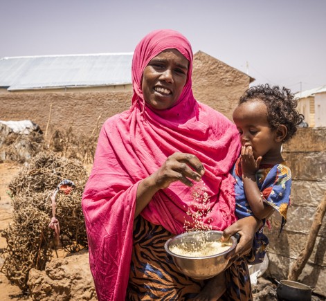 Ayaan holds her young son and bowl of grains 