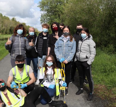 Nine youths in face masks posing after picking litter up from canal banks