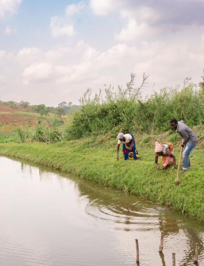 Three farmers tending to dam banks in Malawi village