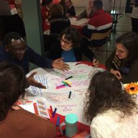 Five people at desk discussing SDGs and writing down notes