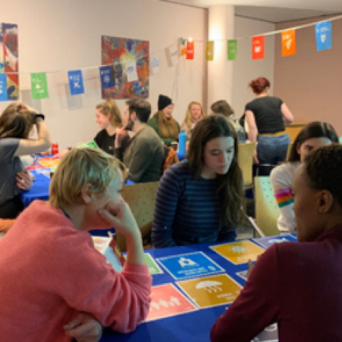 Room filled with tables and bunting with people discussing SDGs