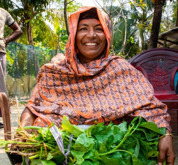 Asma Begum shows off vegetables she is growing on her farm in Bangladesh