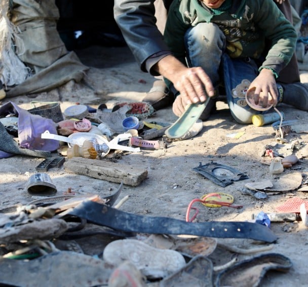A young boy sorting through a rubbish pile for metal 