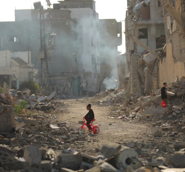 Child on tricycle cycles through destroyed buildings in Gaza
