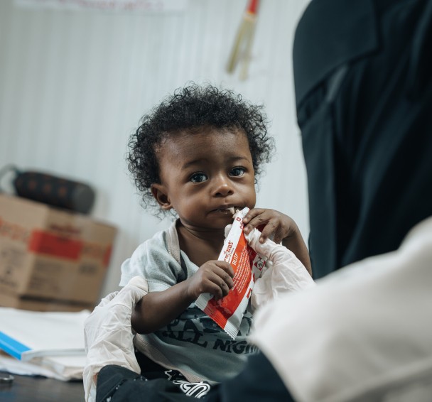 Basam* (10 months) eating nutritional supplements at Concern supported health clinic in one of the displacement camps in Lahj Governorate, Yemen