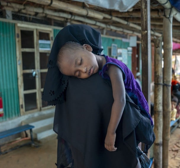 A baby sleeps on his mother's shoulder