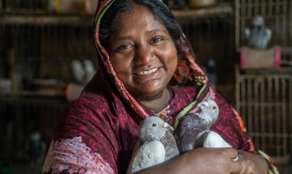Baby (35) raises pigeons in cages inside her small tin shed home