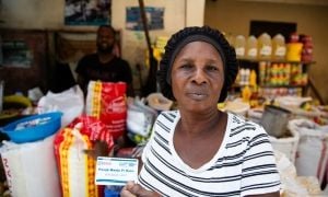 A participant in Concern&#039;s food voucher system buying provisions from a vendor in Cite Soleil, Haiti