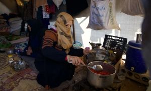 Reem* (30) prepares food for her husband Jaafar* (32) and her children inside their tent in the Ahl al-Khair camp, Syria.