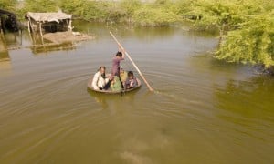 Aqib Aliin (14) transports people on his curry frying pan in Jhuddo, Sindh, Pakistan, during extensive flooding in 2022.  Photo: Emmanuel Guddo/Concern Worldwide