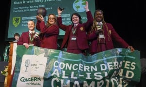 Four team members from Laurel Hill Secondary school stand on a stage with a banner in front of them, after receiving their awards for winning the Concern 2025 Debate final